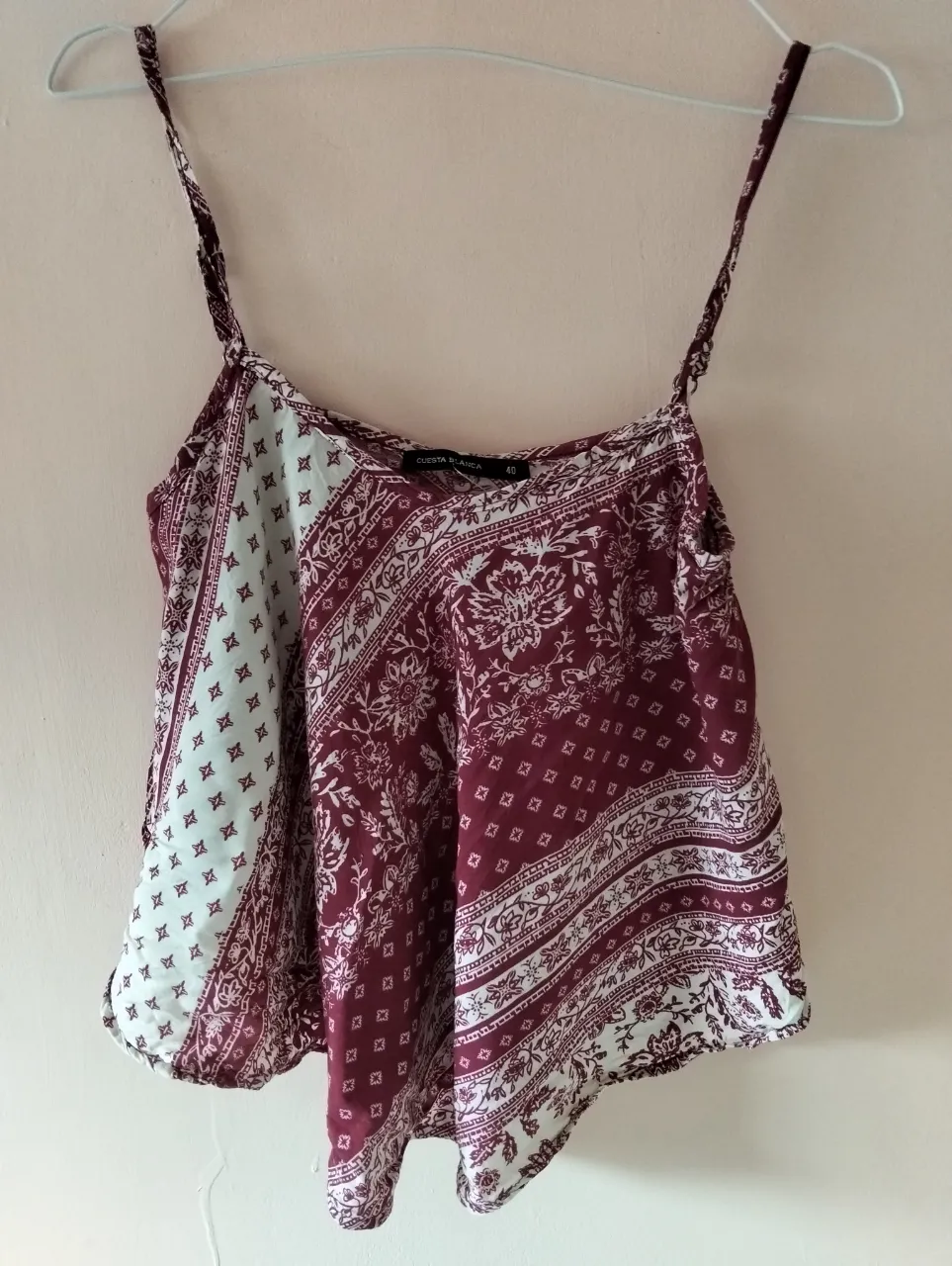 Top de mujer con estampado floral en tonos borgoña y blanco. Diseño con tirantes finos y corte holgado, ideal para un look fresco y casual.