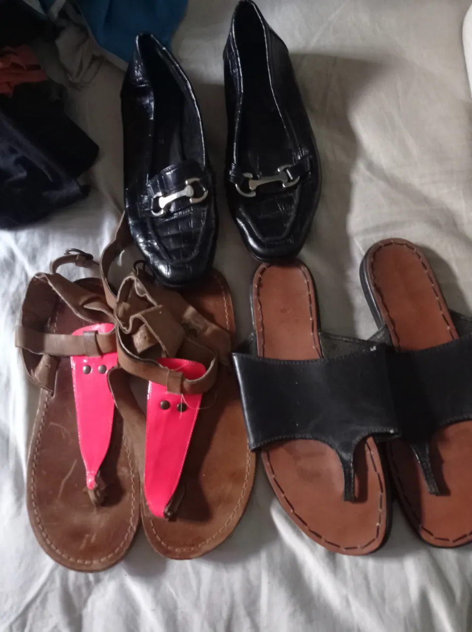 Lote de zapatos variados para mujer. Incluye mocasines negros, sandalias marrones y fucsias, ojotas negras y marrones, zapatillas blancas, zapatillas rosas, zapatillas azules, borcegos marrones y botitas marrones.