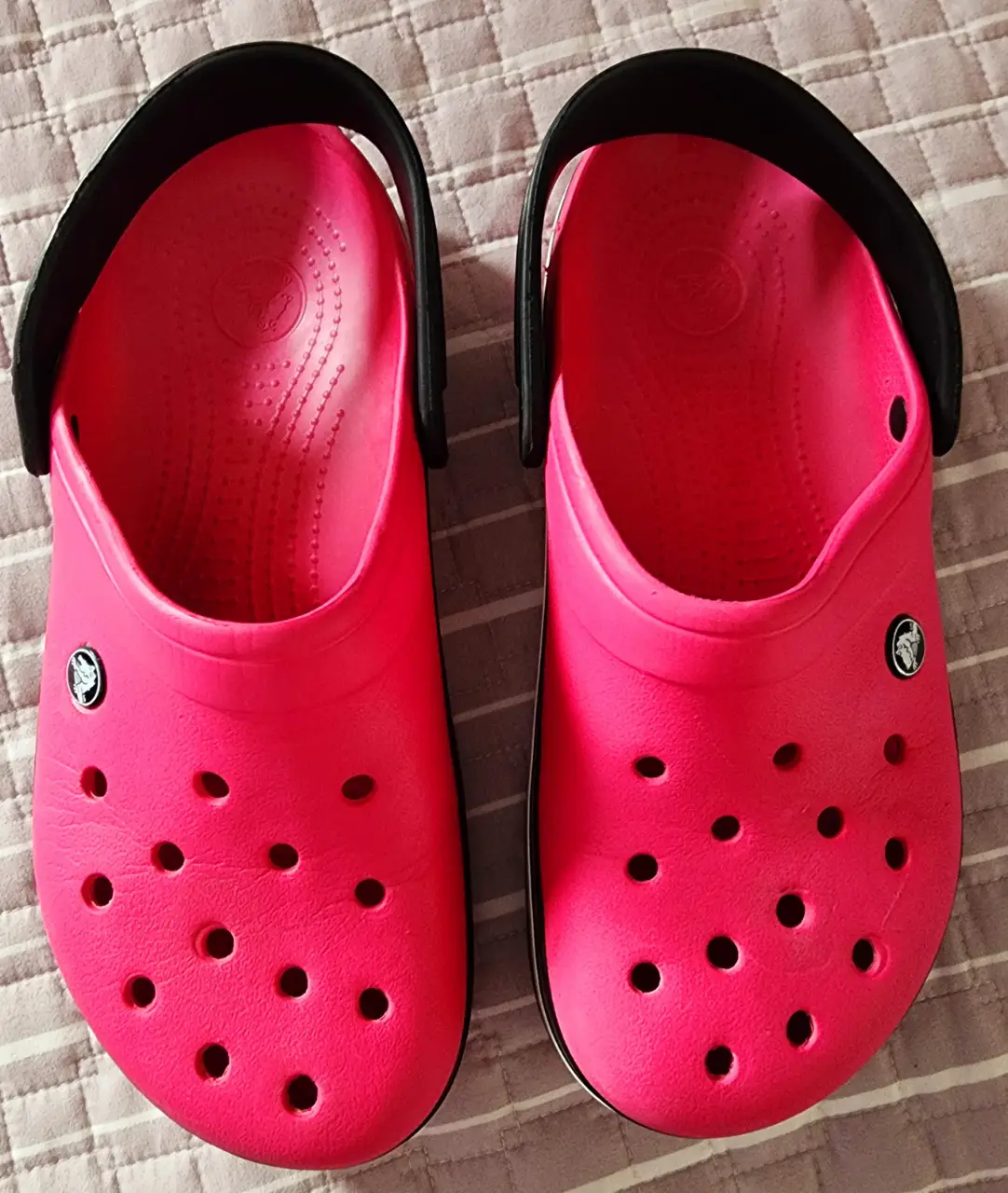 Zuecos Crocs rosados con detalles en negro. Cómodos y versátiles, ideales para el día a día.