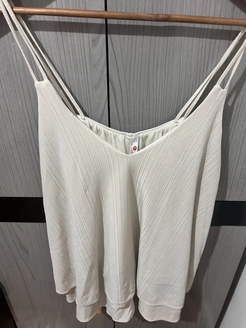 Top blanco con tiras finas y escote en V. Ideal para combinar con diferentes outfits.