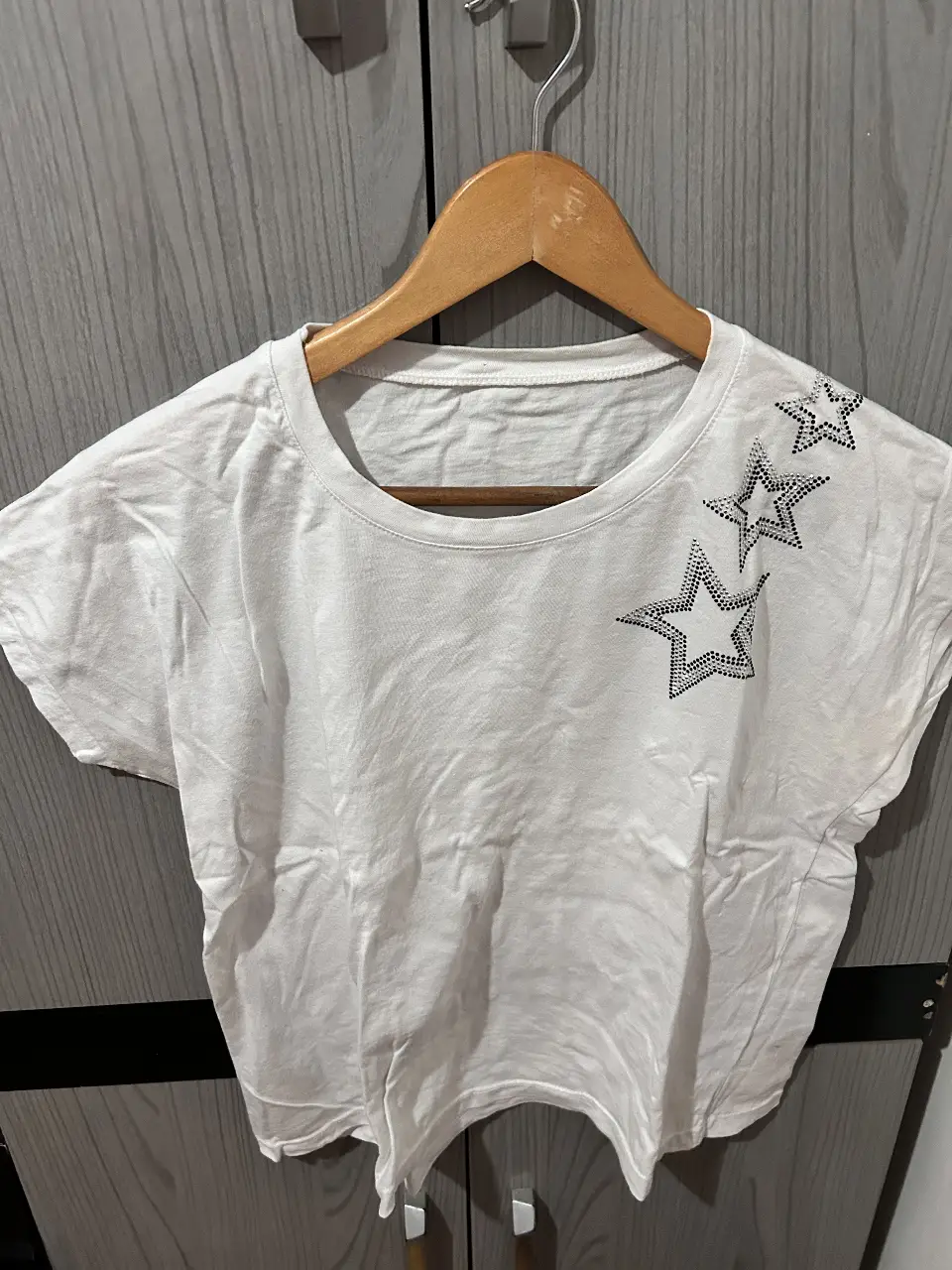 Remera blanca de algodón con diseño de estrellas con brillos en el hombro. Ideal para un look casual y moderno.