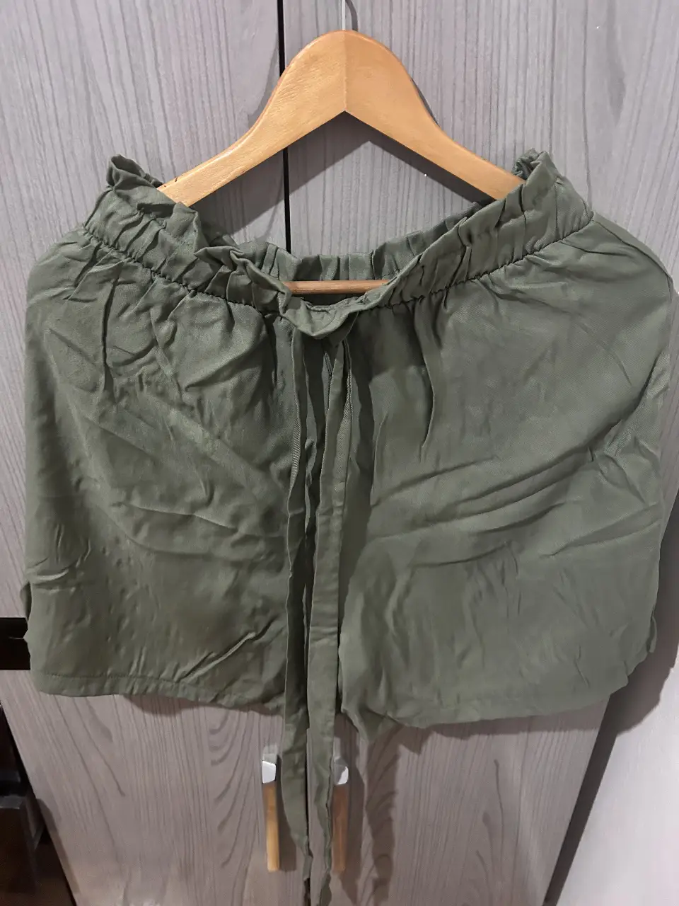 Short de tela verde, tiro alto, con cintura elastizada y lazo para ajustar. Ideal para un look casual y cómodo.