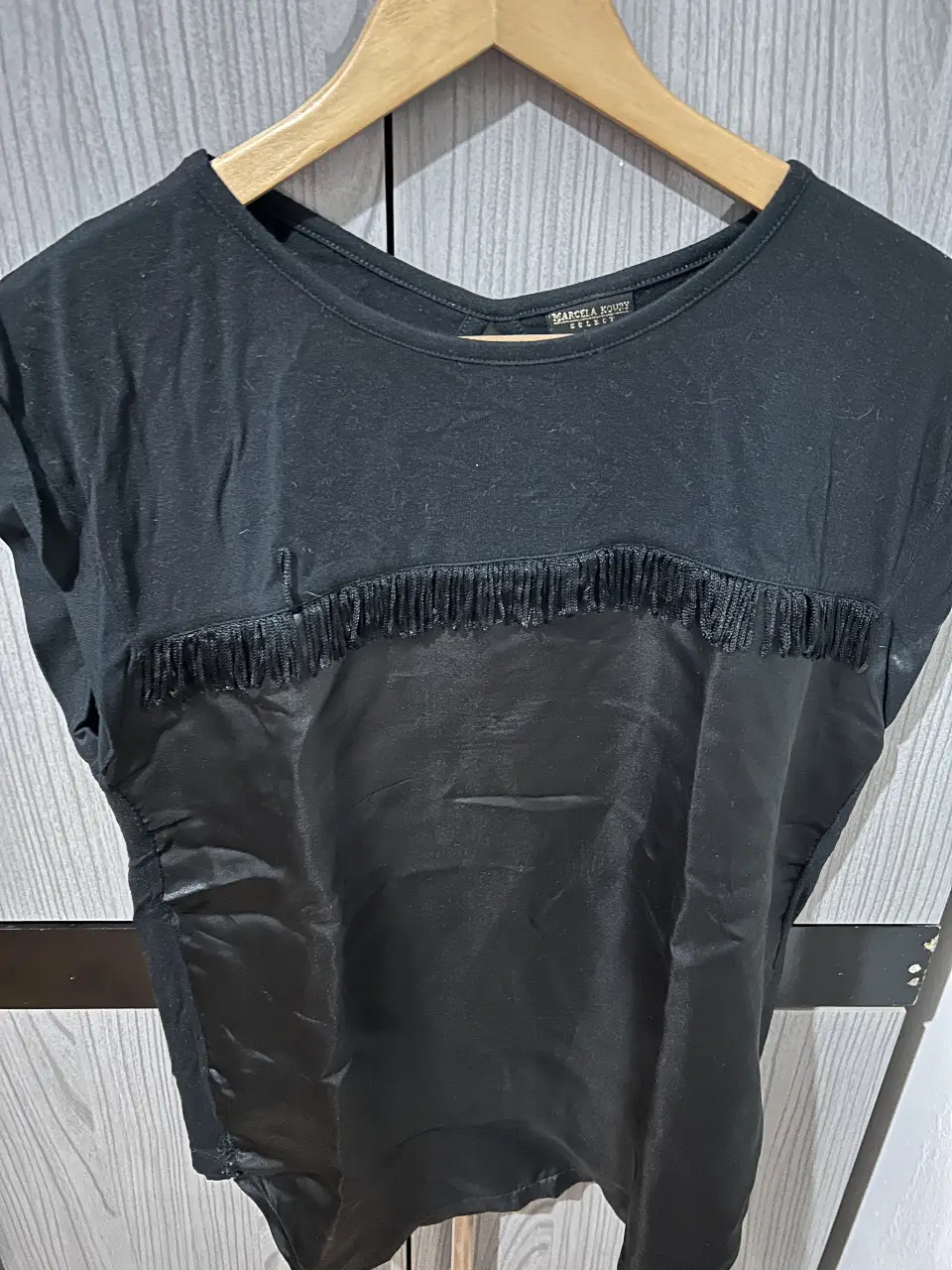 Blusa negra con detalle de flecos en el pecho y espalda descubierta. Ideal para un look casual y moderno.