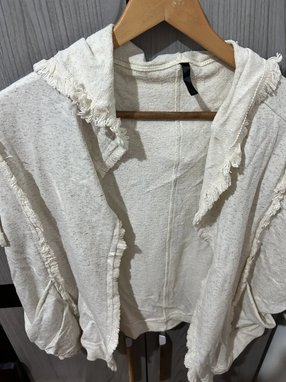 Buzo de cuello redondo con capucha y detalles de flecos en los bordes. Ideal para un look casual y cómodo.
