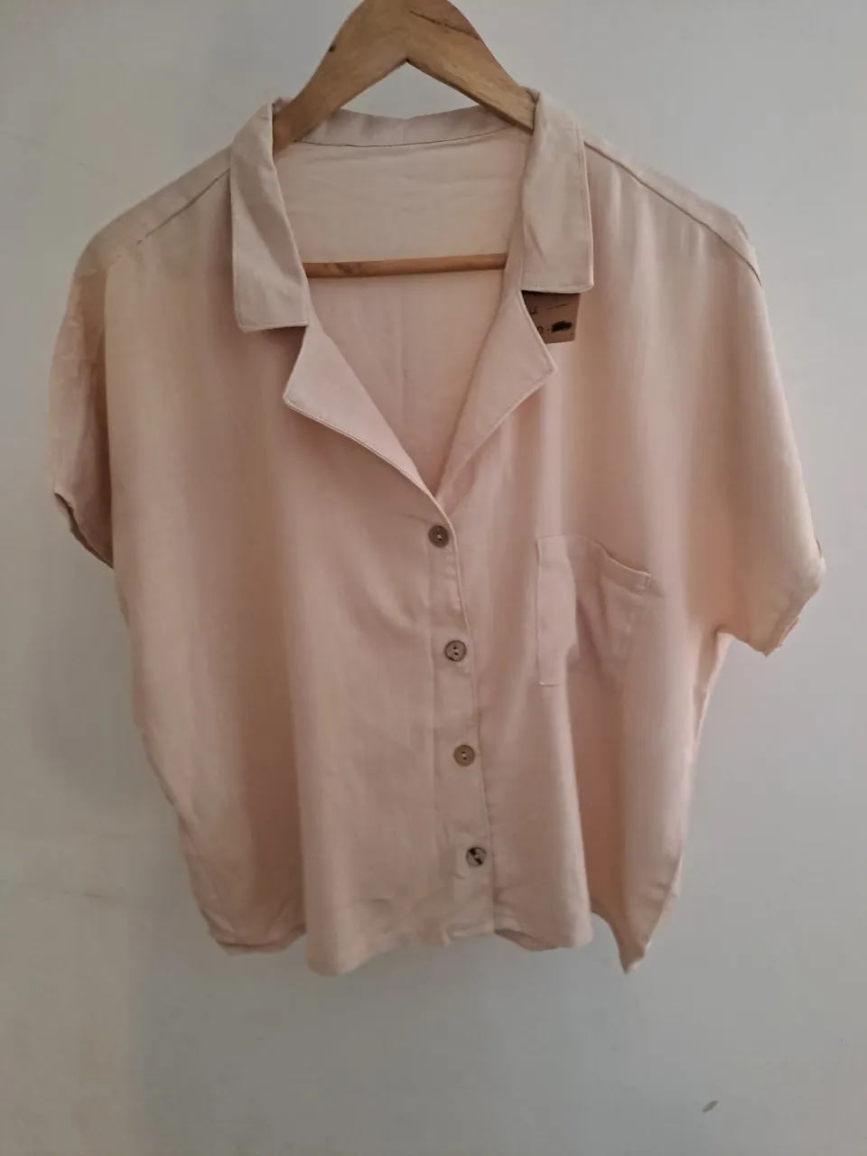 Camisa de lino color crudo, con botones al frente y un bolsillo en el pecho. Manga corta y cuello solapa. Ideal para un look casual y fresco.