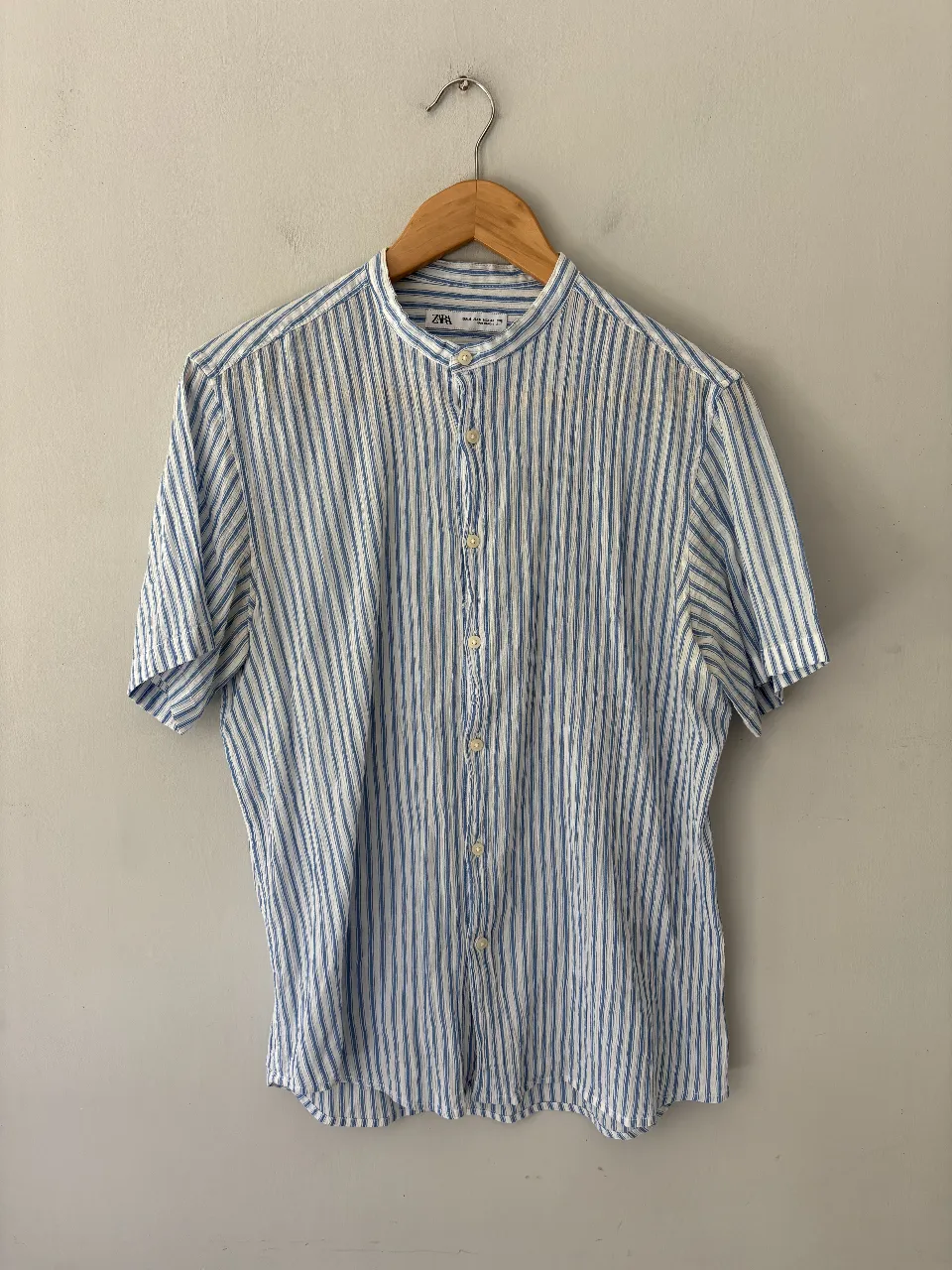 Camisa tipo lino a rayas celestes y blancas, con cuello mao y botones al frente. Manga corta, ideal para un look fresco y casual.