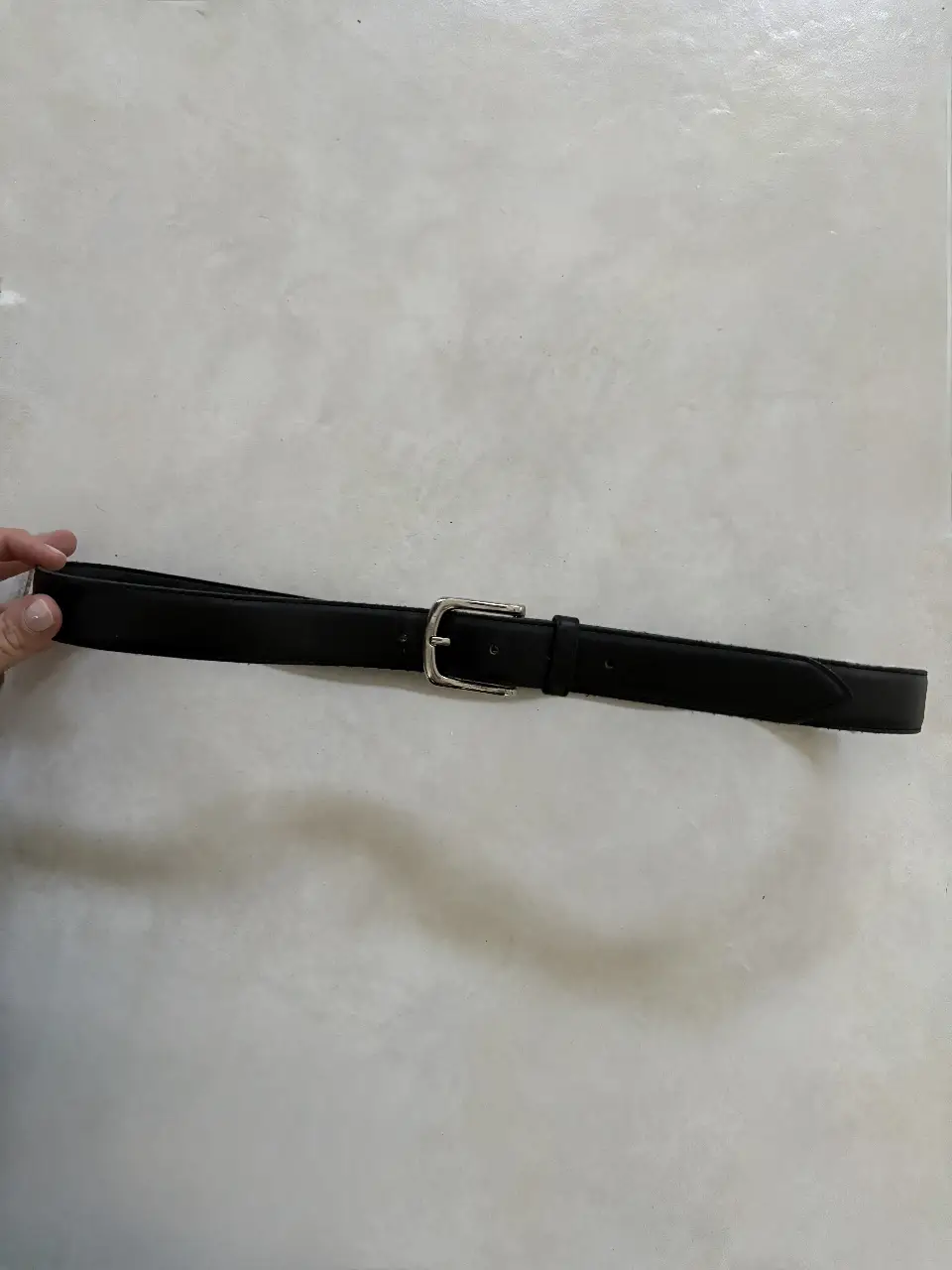 Cinturón de cuero negro para hombre, con hebilla plateada. Ideal para completar cualquier look casual o formal.