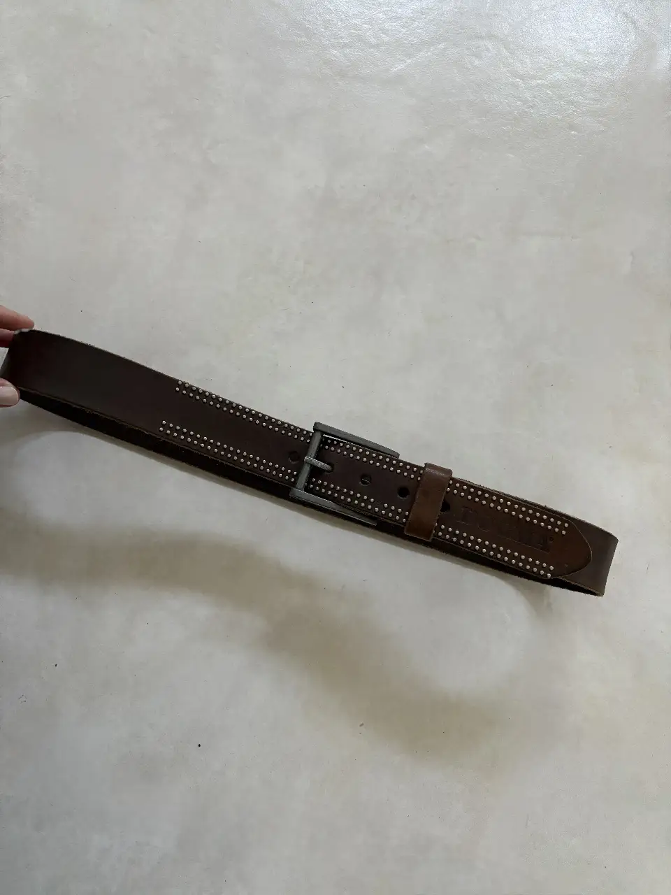 Cinturón de cuero marrón con detalles de tachas plateadas y hebilla metálica. Ideal para un look casual y con estilo.