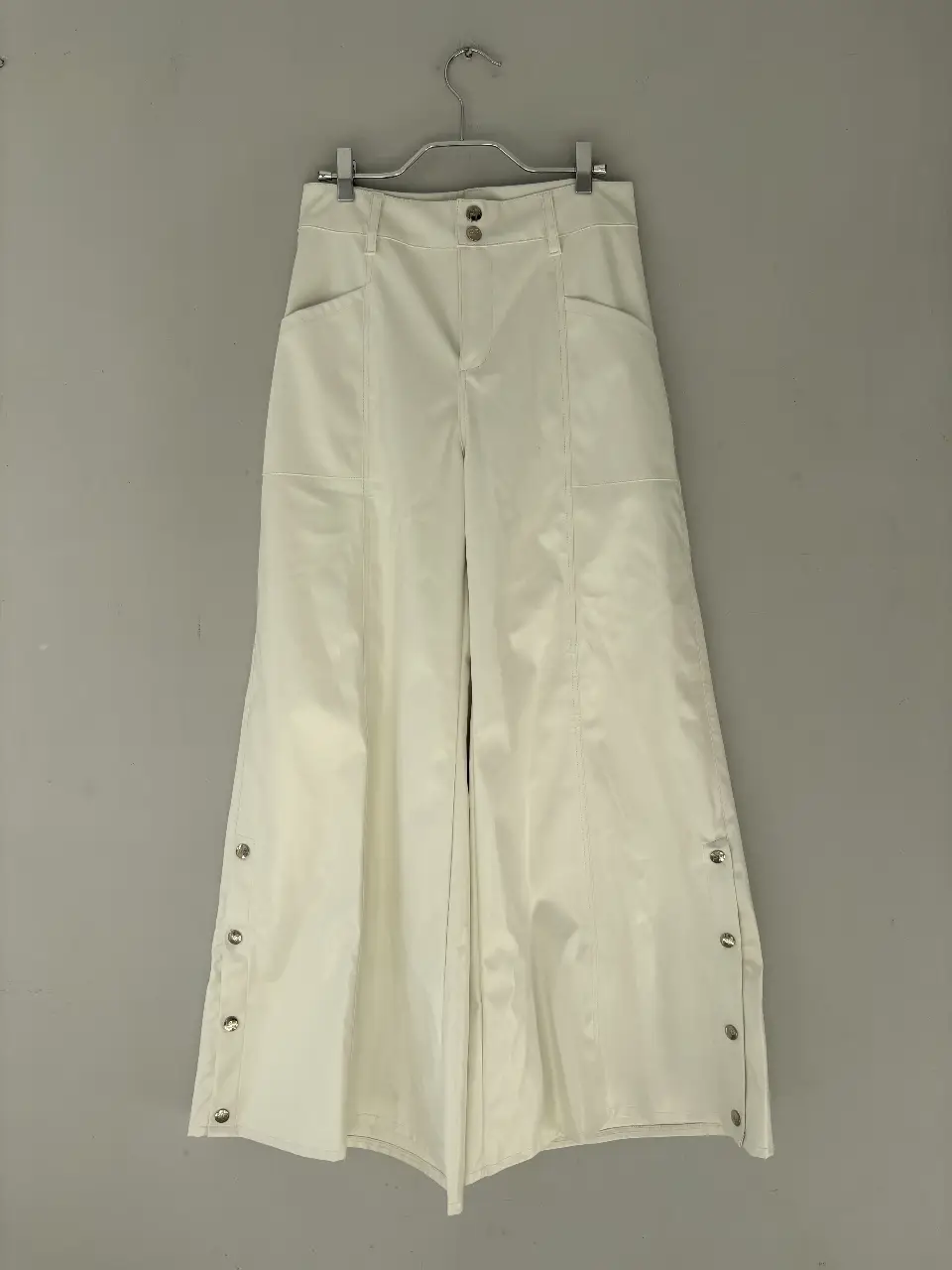 Pantalón cuero blanco con botones laterales. Tiro alto y corte ancho, ideal para un look elegante y moderno.