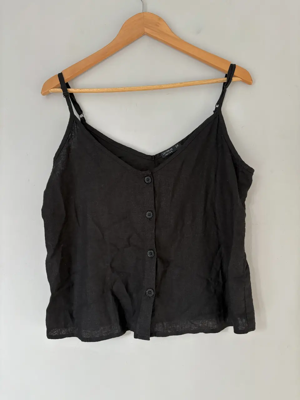 Top negro de lino con breteles finos ajustables y botones delanteros. Ideal para un look casual y fresco.