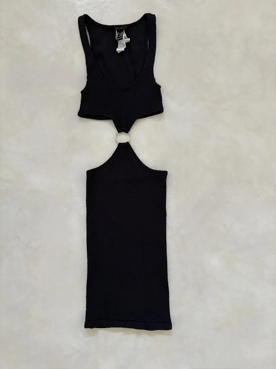 Vestido mini negro con diseño cut-out y detalle de aro metálico. Ideal para un look moderno y audaz.