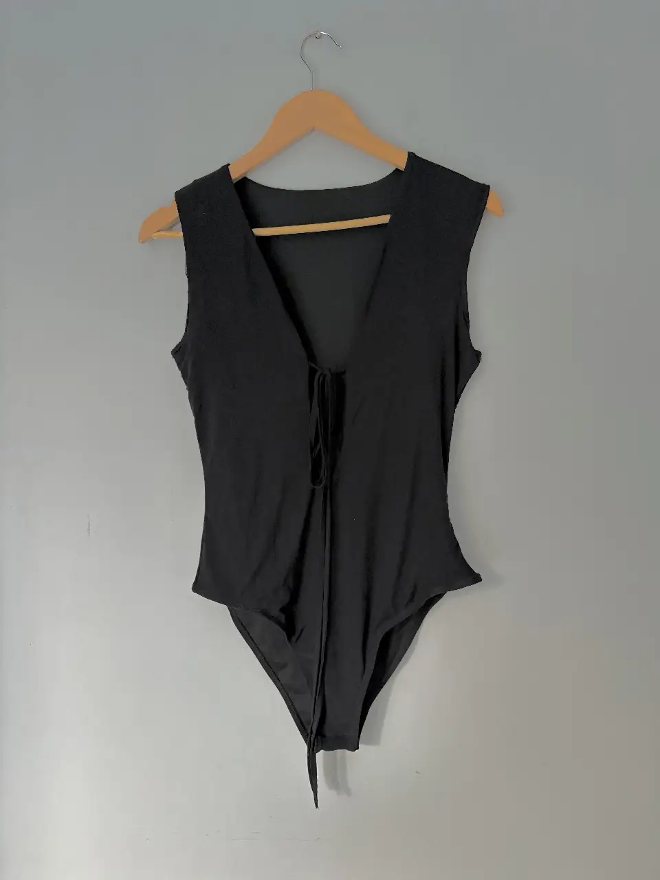 Body negro con escote en V y detalle de lazo frontal. Ideal para un look elegante y moderno.