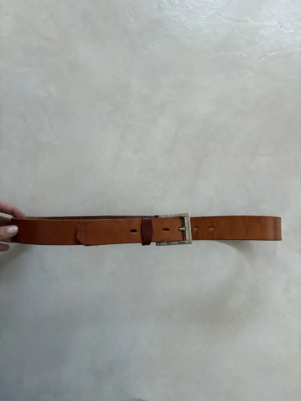 Cinturón de cuero marrón con hebilla plateada. Ideal para uso diario, combina con jeans y pantalones de vestir.