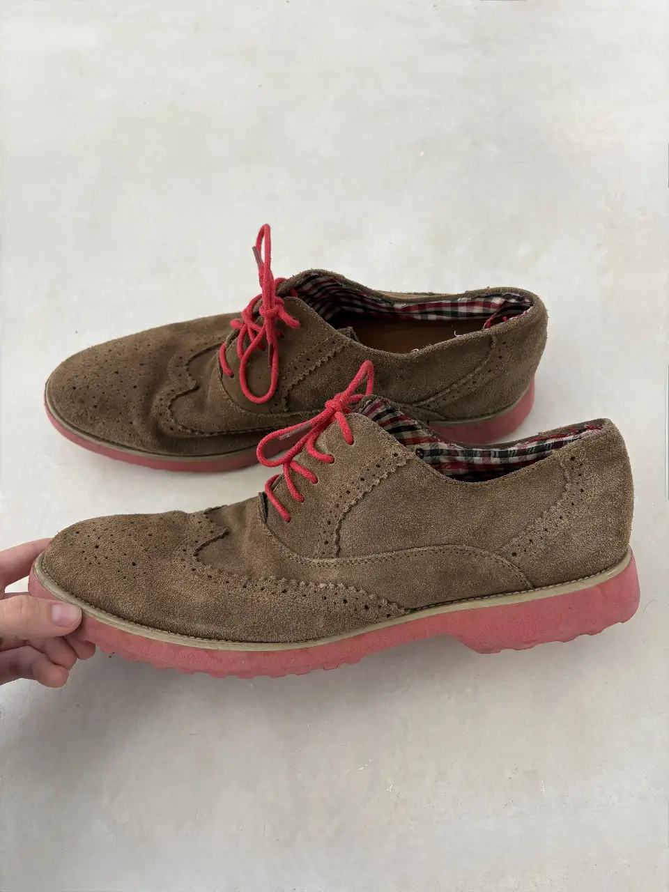 Zapatos de hombre tipo Oxford de gamuza marrón con suela y cordones rojos. Un calzado elegante y versátil para un look casual.