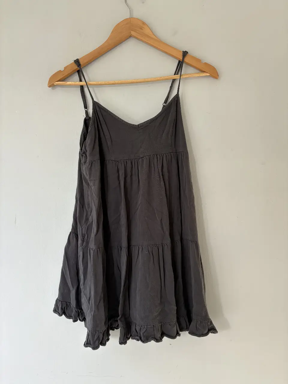 Vestido mini de tirantes finos, color gris oscuro, con volados en la falda. Ideal para un look casual y fresco.
