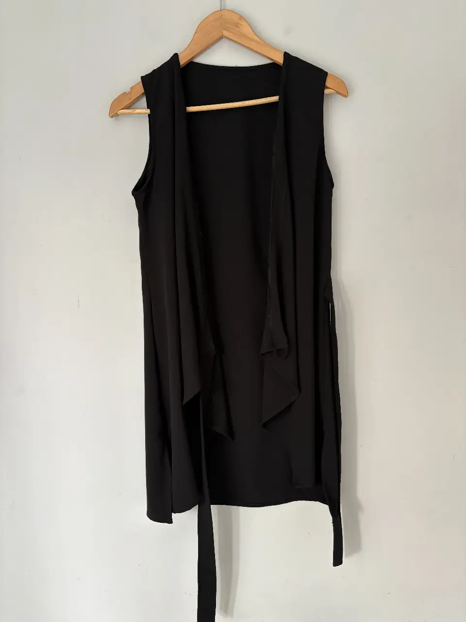 Chaleco negro sin mangas, con diseño abierto y lazos para atar. Ideal para un look elegante y versátil.