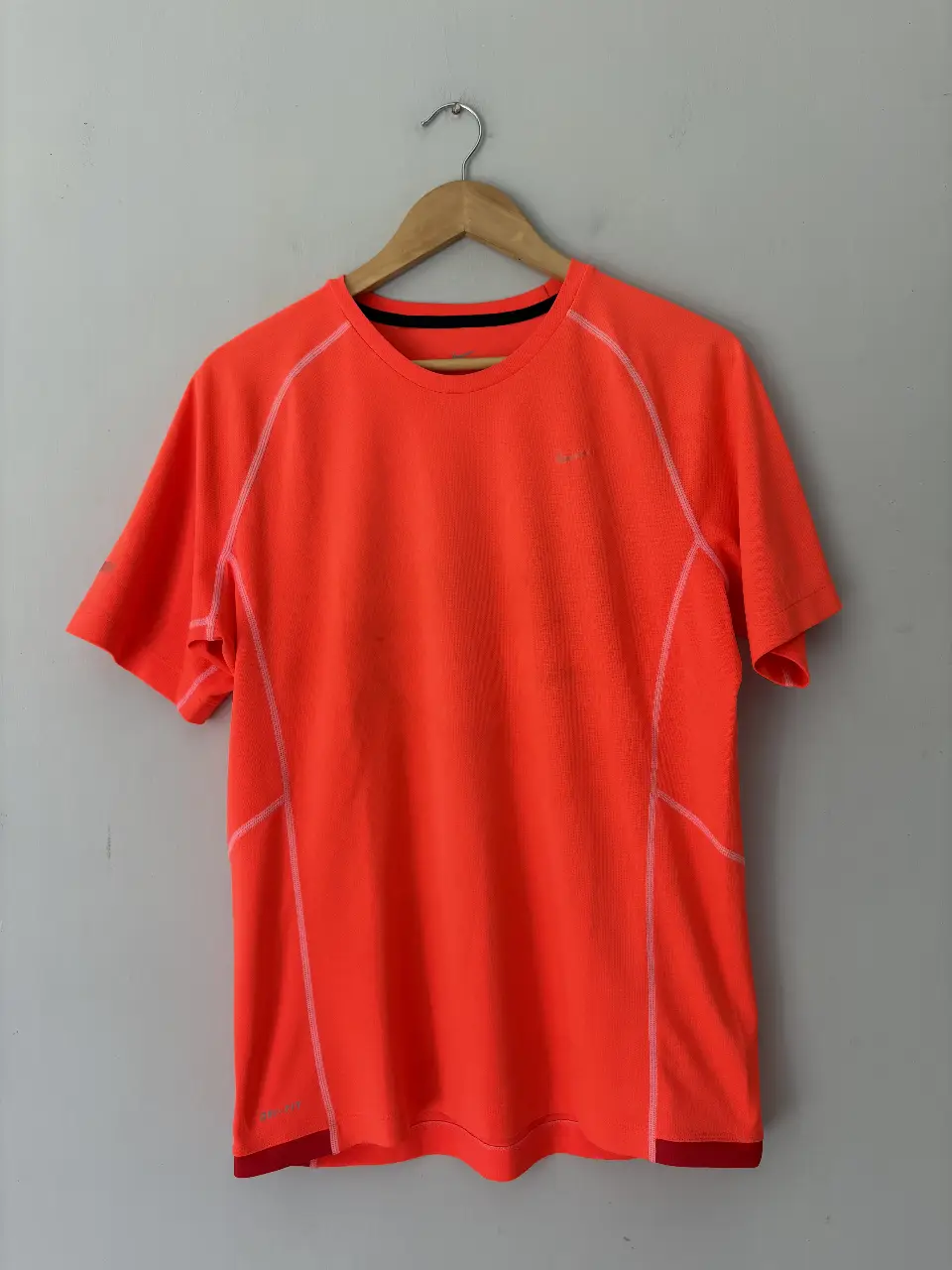 Remera deportiva naranja de hombre, con detalles en blanco y logo de la marca. Ideal para running y entrenamientos.