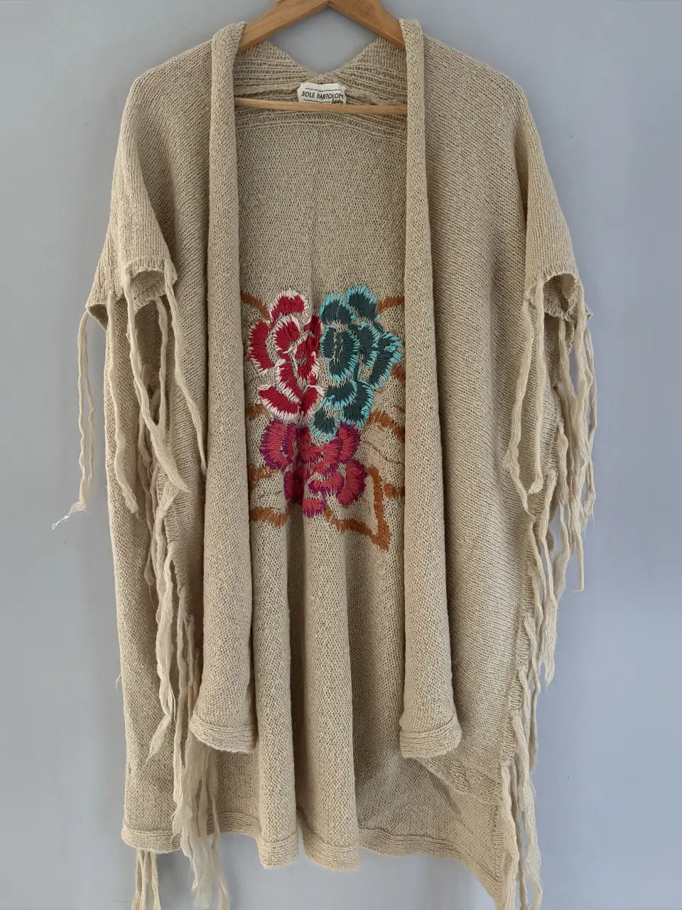 Saco tejido a mano de color crudo con bordado floral en tonos rojo, azul y rosa. Ideal para un look bohemio y artesanal.