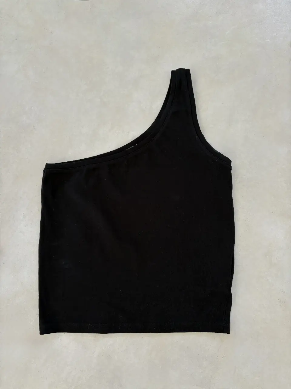 Remera negra de un solo hombro, ideal para un look moderno y versátil. Perfecto para combinar con jeans o faldas.