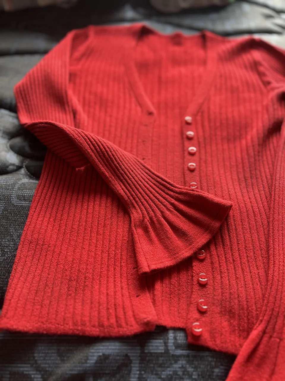Cardigan rojo tejido con botones y mangas acampanadas. Ideal para un look elegante y moderno.