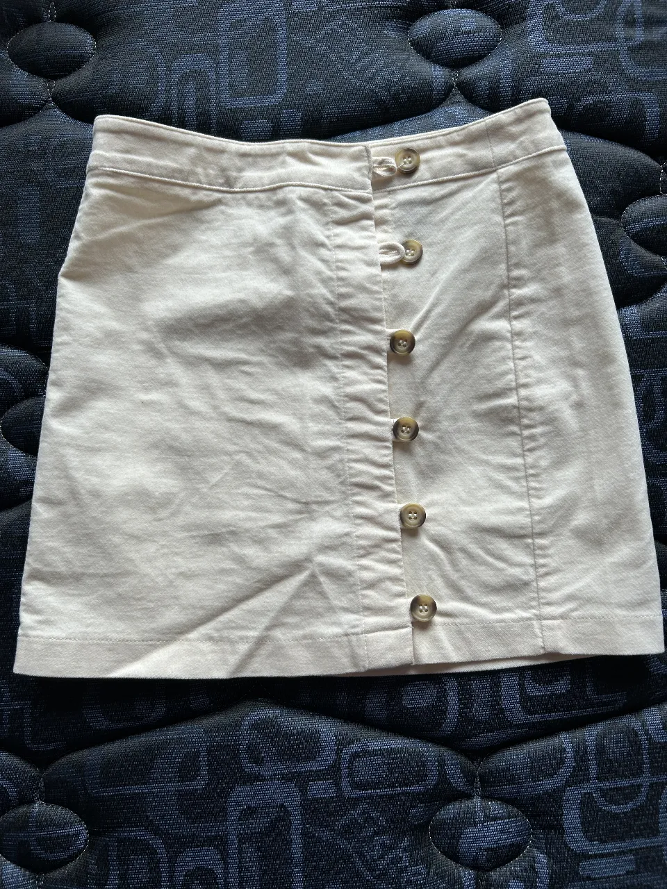 Minifalda de color crudo con botones delanteros. Ideal para un look casual y versátil.