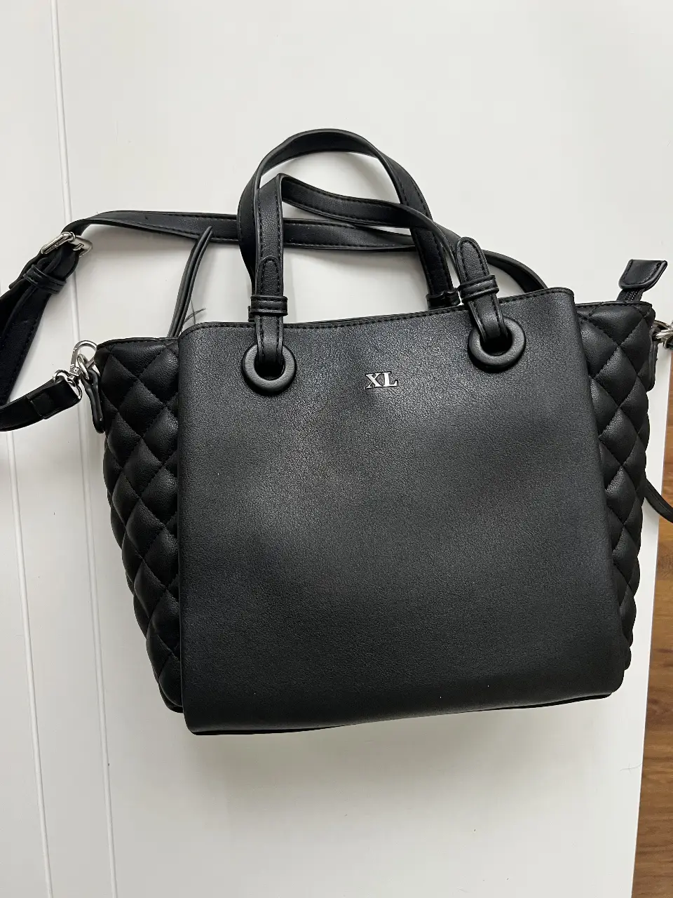 Cartera negra con diseño acolchado, ideal para llevar al hombro o cruzada. Cuenta con manijas cortas y una correa larga ajustable. Perfecta para un look elegante y funcional.