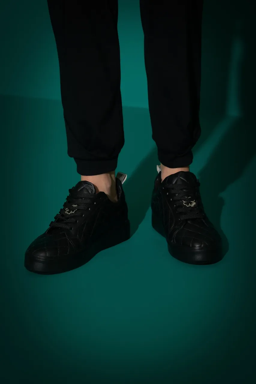 Zapatillas urbanas negras, con un diseño acolchado tipo matelassé y detalles plateados en el talón. Perfectas para un look casual y moderno. la plantilla mide 24cm