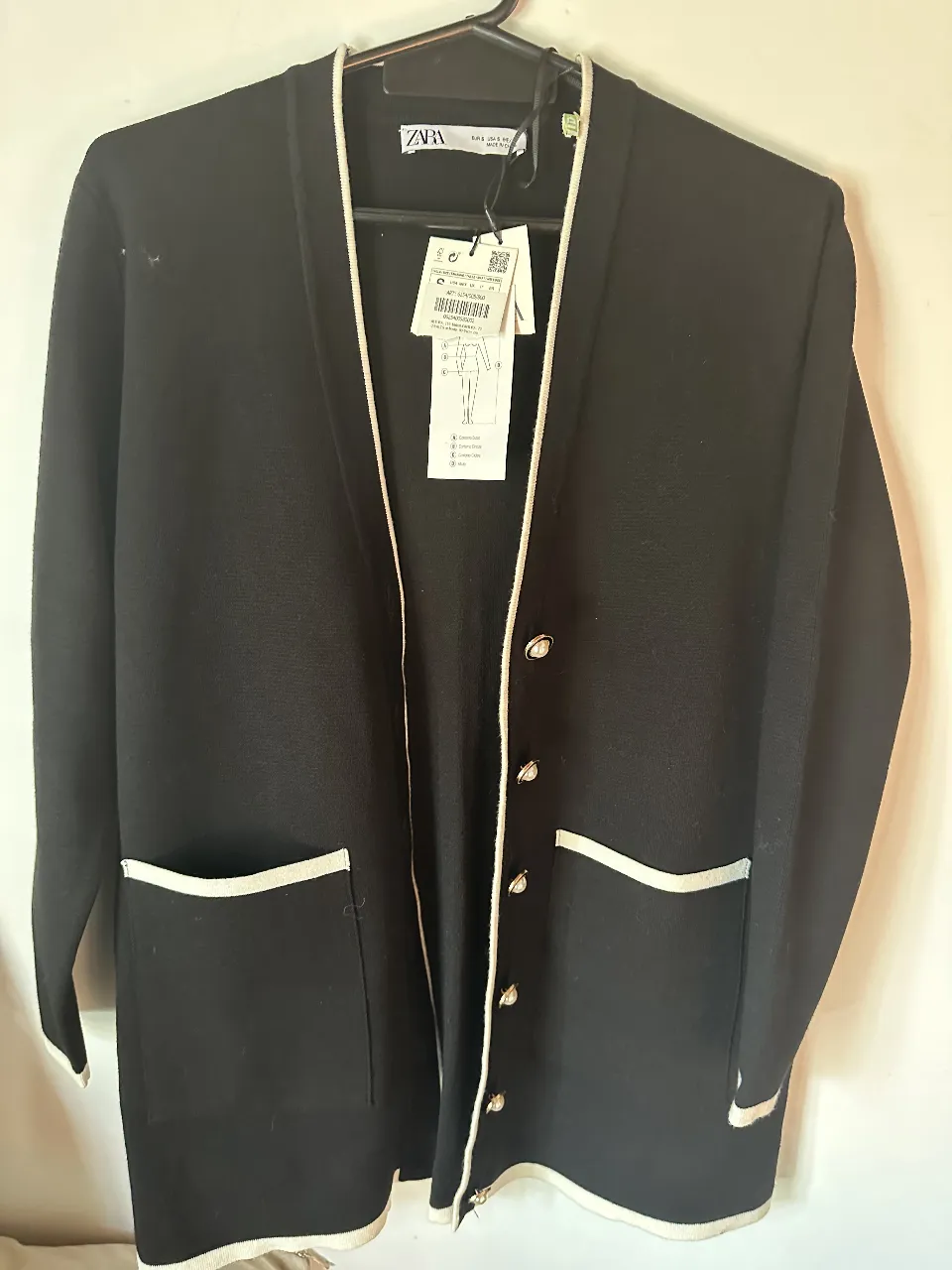 Cardigan largo de mujer, color negro con detalles en blanco. Con botones y bolsillos. Ideal para un look elegante y versátil.