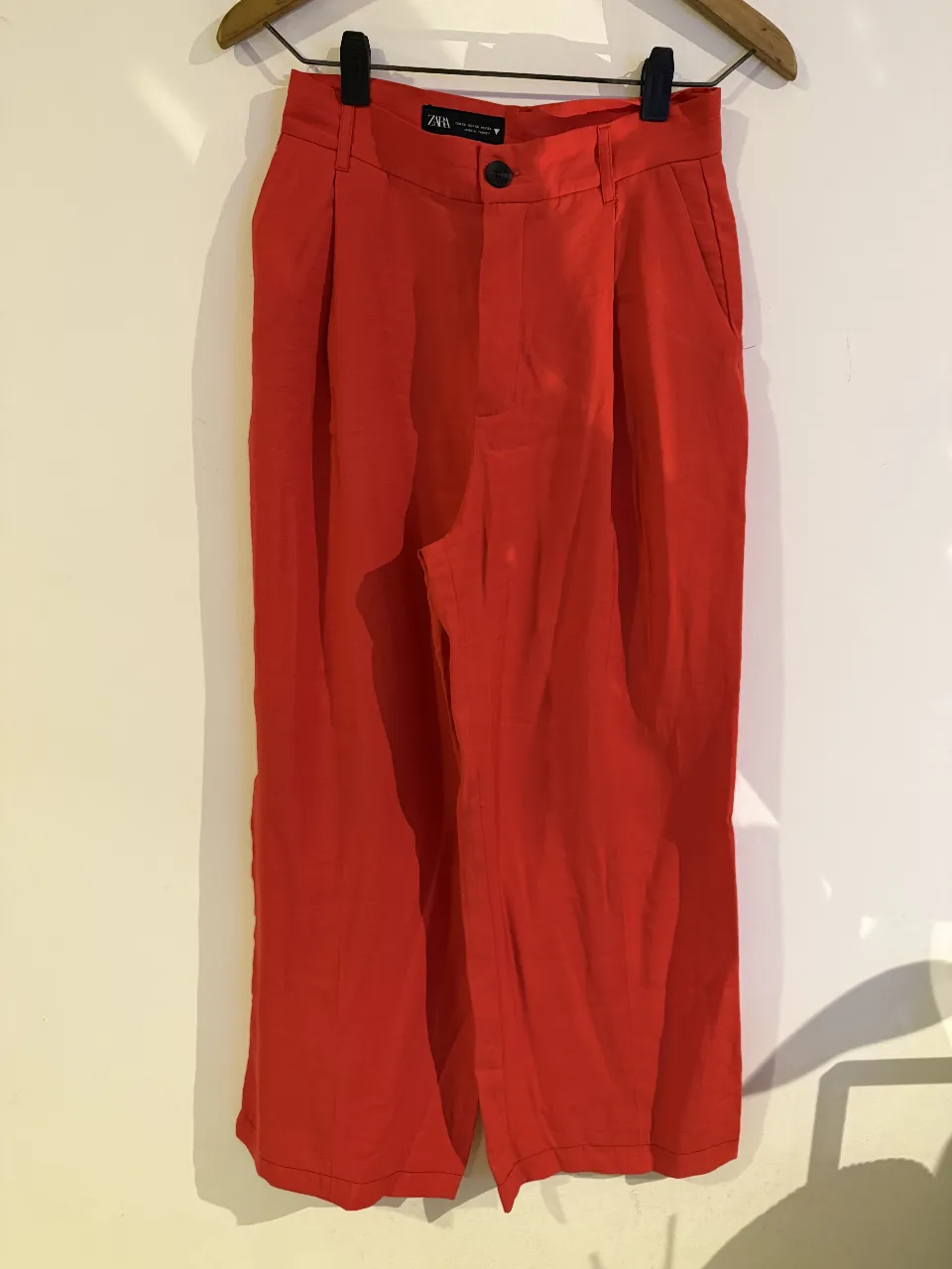 Pantalón sastrero rojo de Zara, tiro alto, con pinzas y bolsillos. Ideal para un look elegante y moderno.