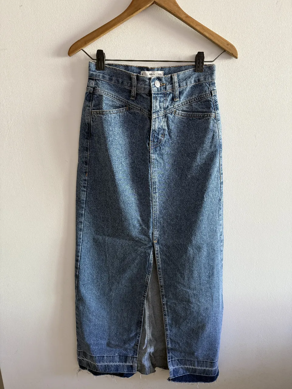 Pollera larga de jean azul, con abertura frontal. Tiro alto, ideal para un look casual y moderno. Marca MNG.