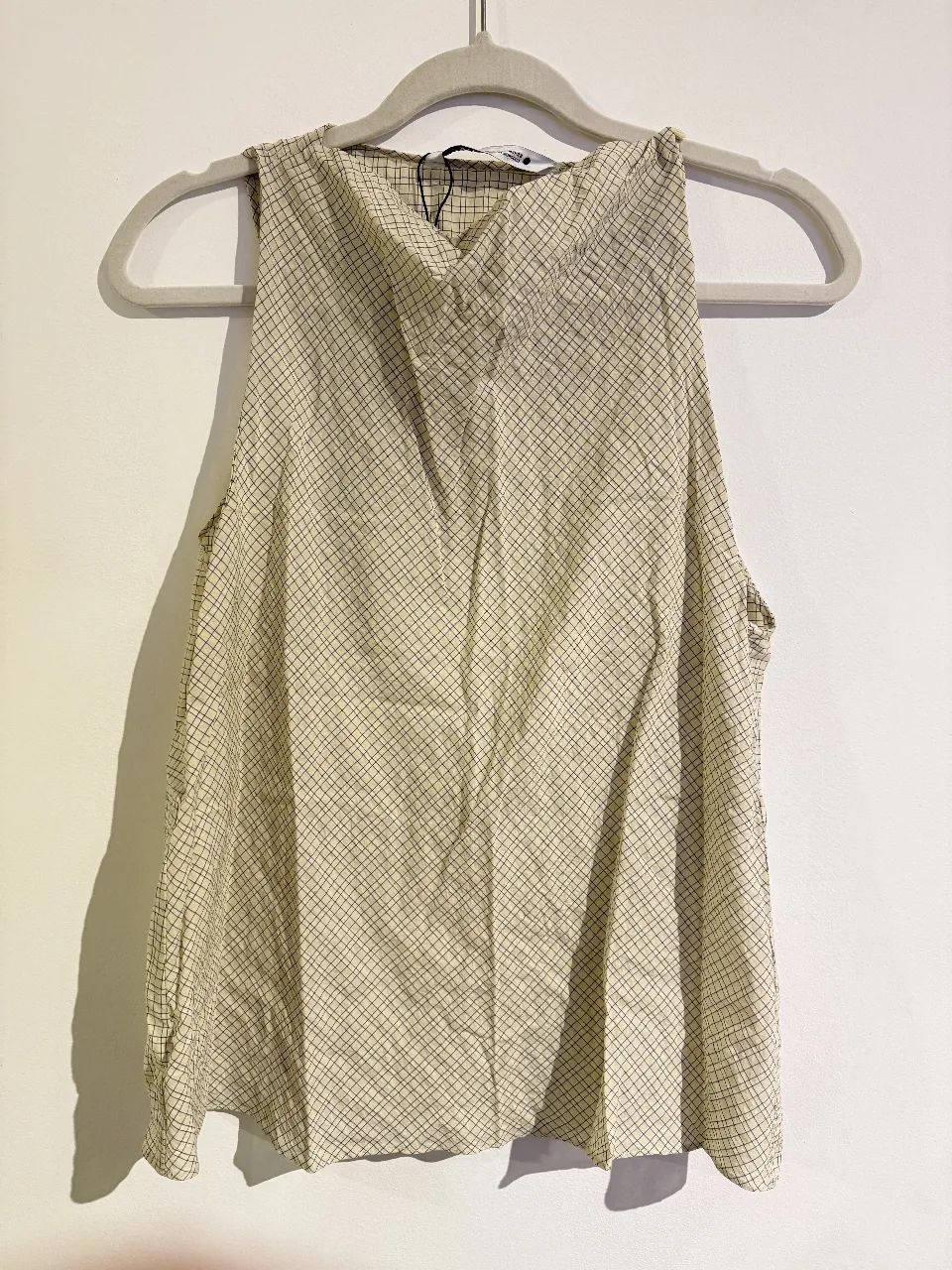 Blusa sin mangas de mujer, con estampado de cuadros en color crudo. Ideal para un look fresco y casual.