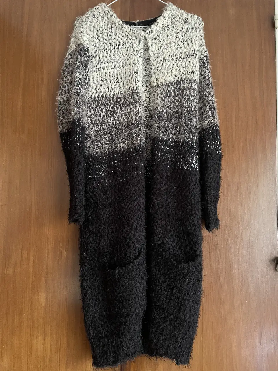 Cardigan largo de tejido grueso con diseño a rayas en tonos blanco, gris y negro. Ideal para un look casual y abrigado.