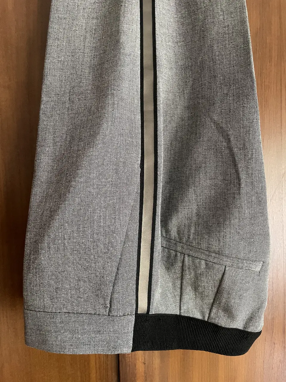 Pantalón sastrero gris con detalle de cinta negra y plateada en la pierna. Tiro alto, con cierre y botón. Marca Zara.