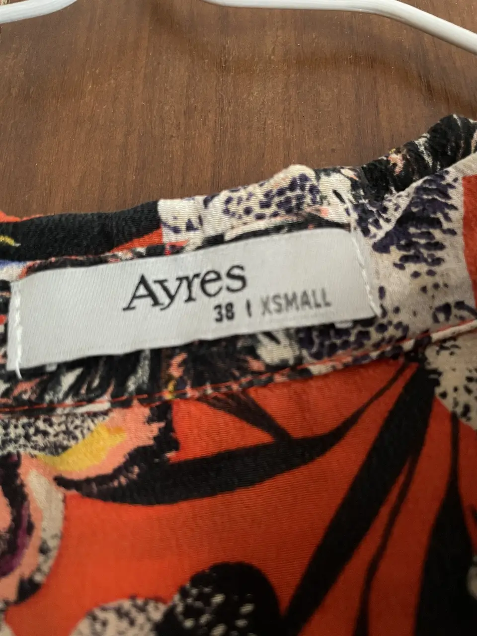Camisa estampada de la marca Ayres, con un diseño floral vibrante en tonos rojos, negros, blancos y azules. Talle XS, ideal para un look casual y con estilo.