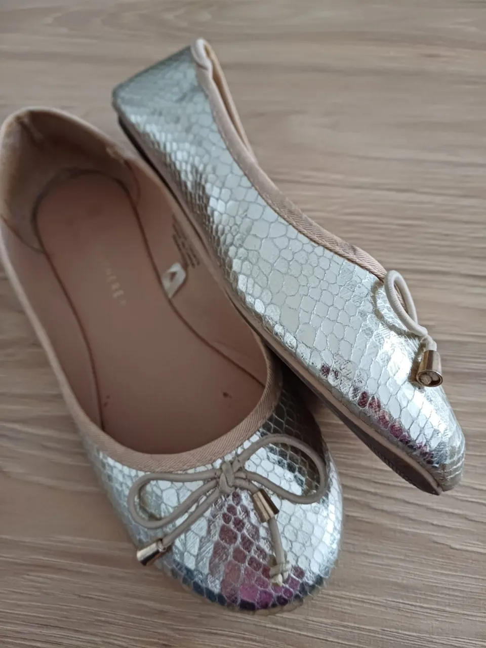 Ballerinas doradas con detalle de moño y dije dorado. Ideales para un look elegante y cómodo.