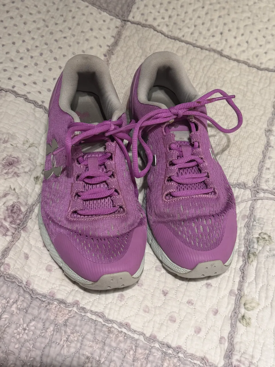 Zapatillas Under Armour Charged Assert 9 para mujer en color violeta con detalles en gris. Ideales para running y entrenamiento, ofrecen comodidad y soporte.