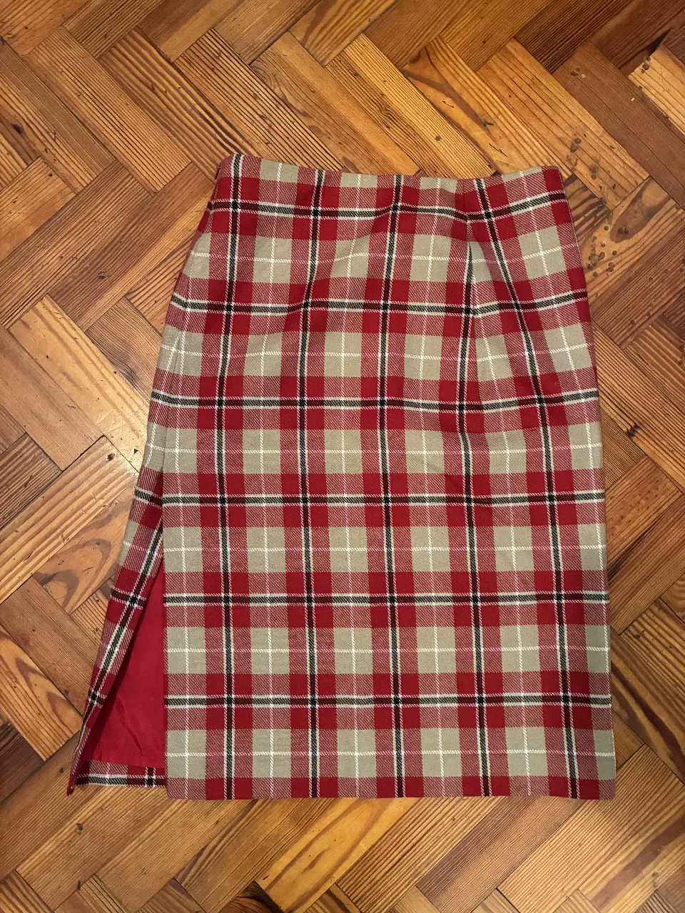 Pollera escocesa roja y beige con detalles en negro y blanco y abertura lateral. Forrada por dentro.  61cm de largo. Talle 1