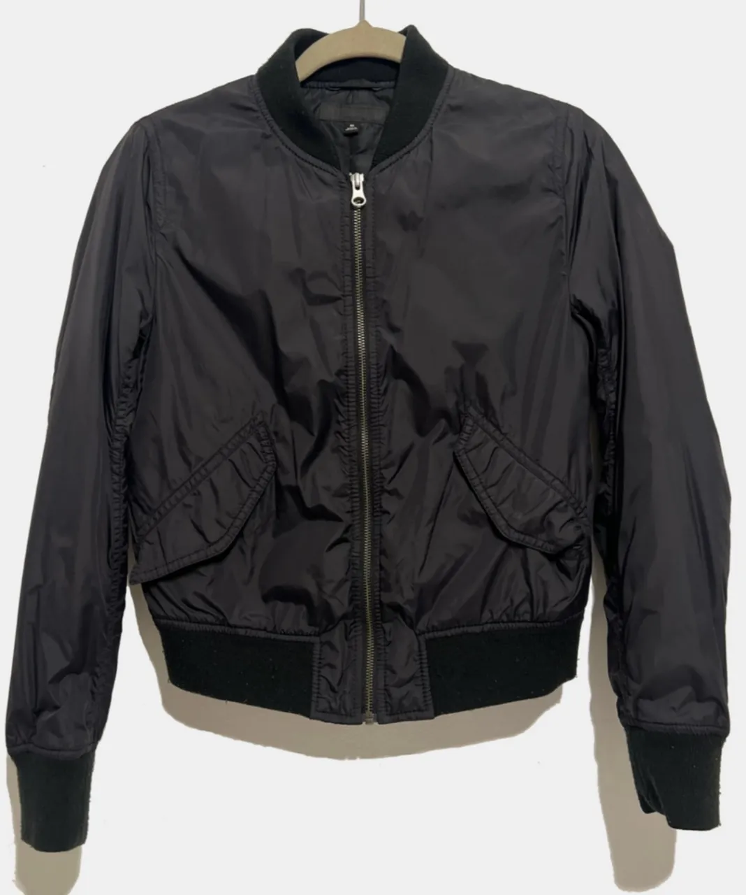 Campera bomber negra para mujer. Confeccionada en un tejido ligero y resistente, perfecta para usar en entretiempo. Cuenta con cierre frontal, bolsillos laterales y puños y cintura elastizados. Es de Uniqlo.