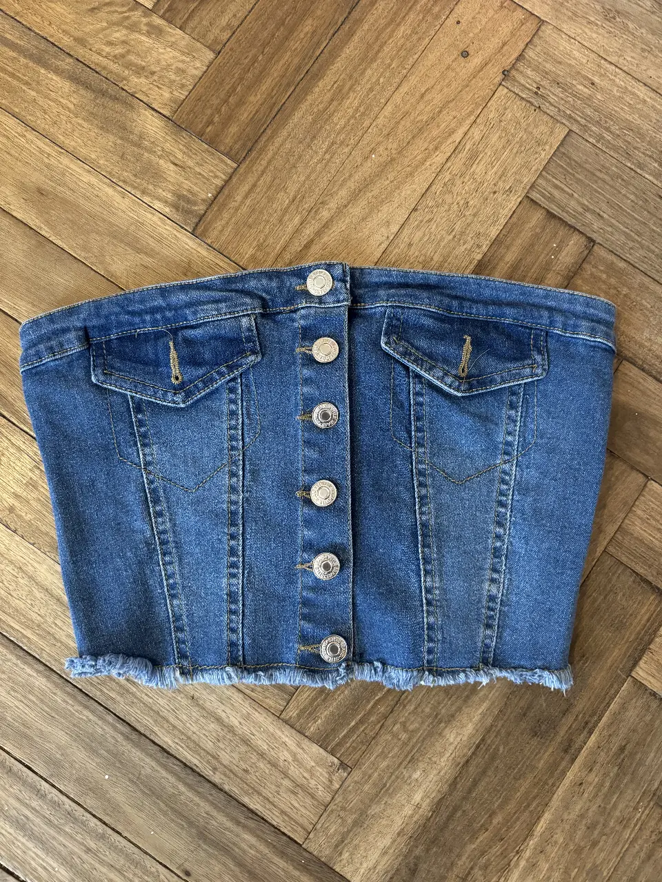 Top tipo corset de jean con botones al frente y flecos en el borde inferior. Ideal para un look casual y canchero.