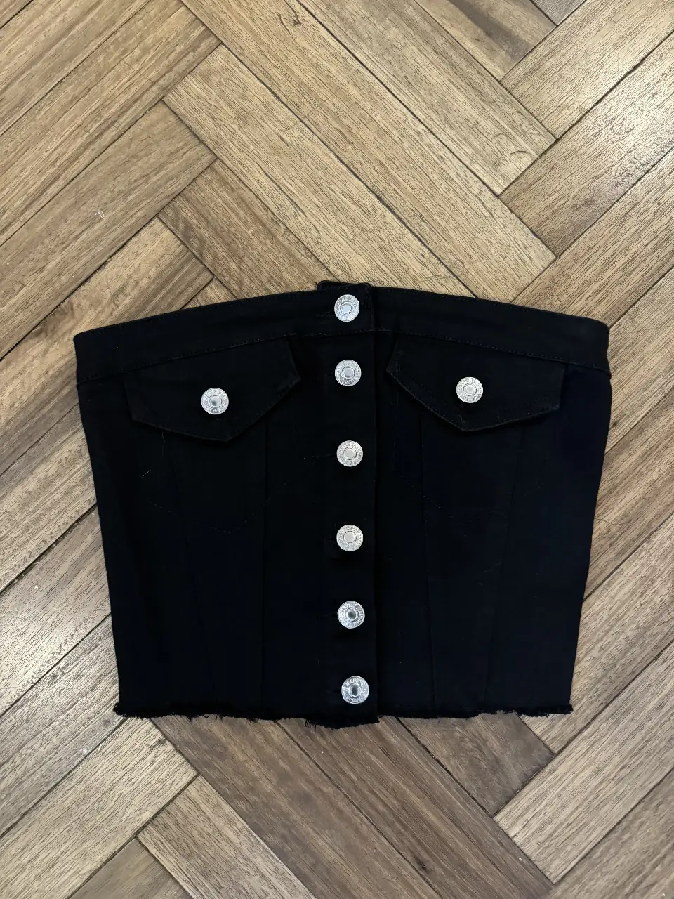 Top tipo corset negro de jean con botones y bolsillos. Ideal para un look casual y moderno.