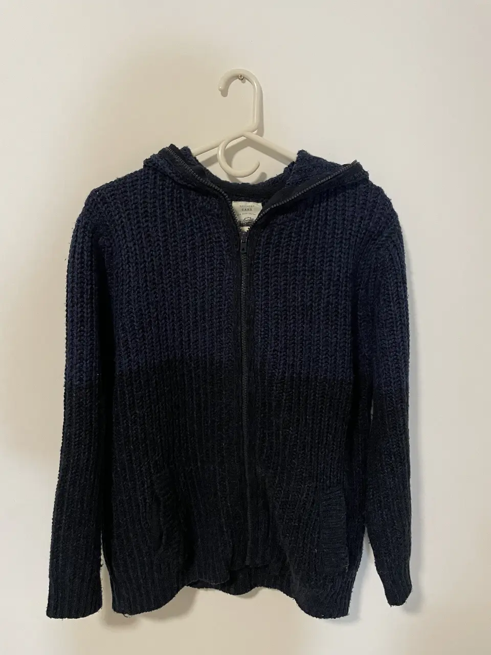Buzo con cierre y capucha, tejido grueso en dos tonos de azul y negro. Ideal para el invierno. Medidas: 60 cm de largo, 55 cm de ancho, 55 cm de largo de manga.