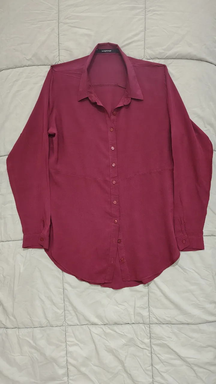 Camisa de vestir color bordó, con botones al frente y cuello clásico. Posee un diseño moderno en la espalda con una abertura y solapa superpuesta. Ideal para un look elegante y sofisticado.