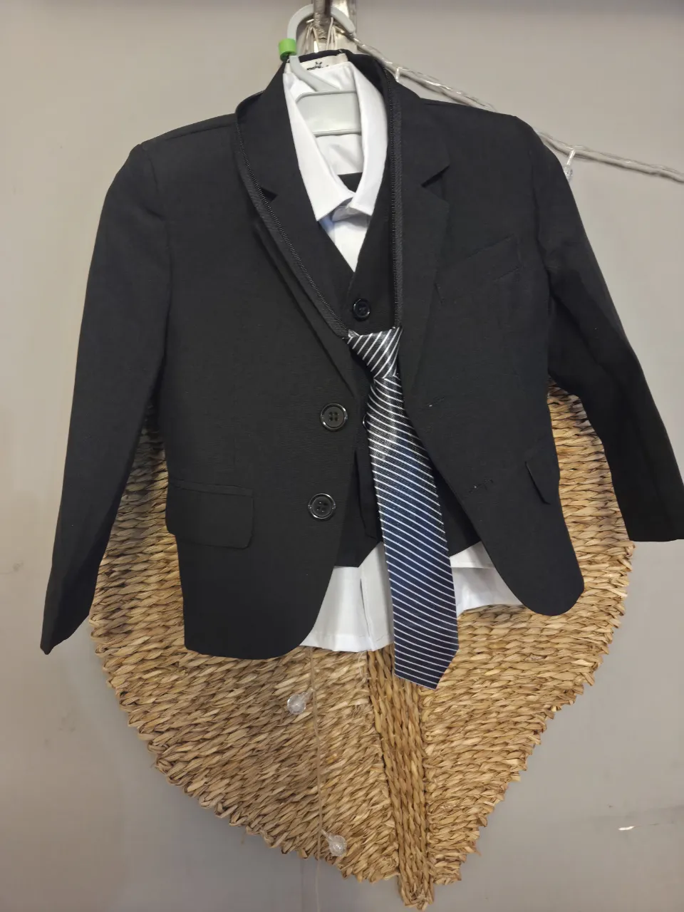 Traje de saco negro, chaleco negro, camisa blanca y corbata a rayas azules y blancas.