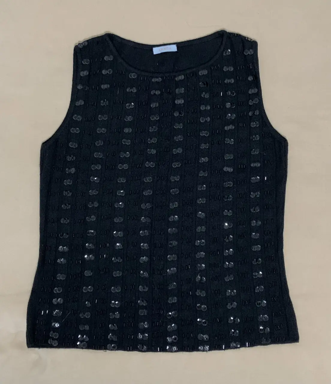 Musculosa negra con lentejuelas y detalles en relieve. Ideal para una salida nocturna o evento especial.