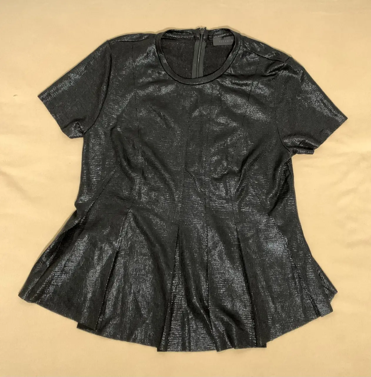 Blusa negra con brillo, corte peplum y cierre en la espalda. Ideal para un look elegante y sofisticado. 