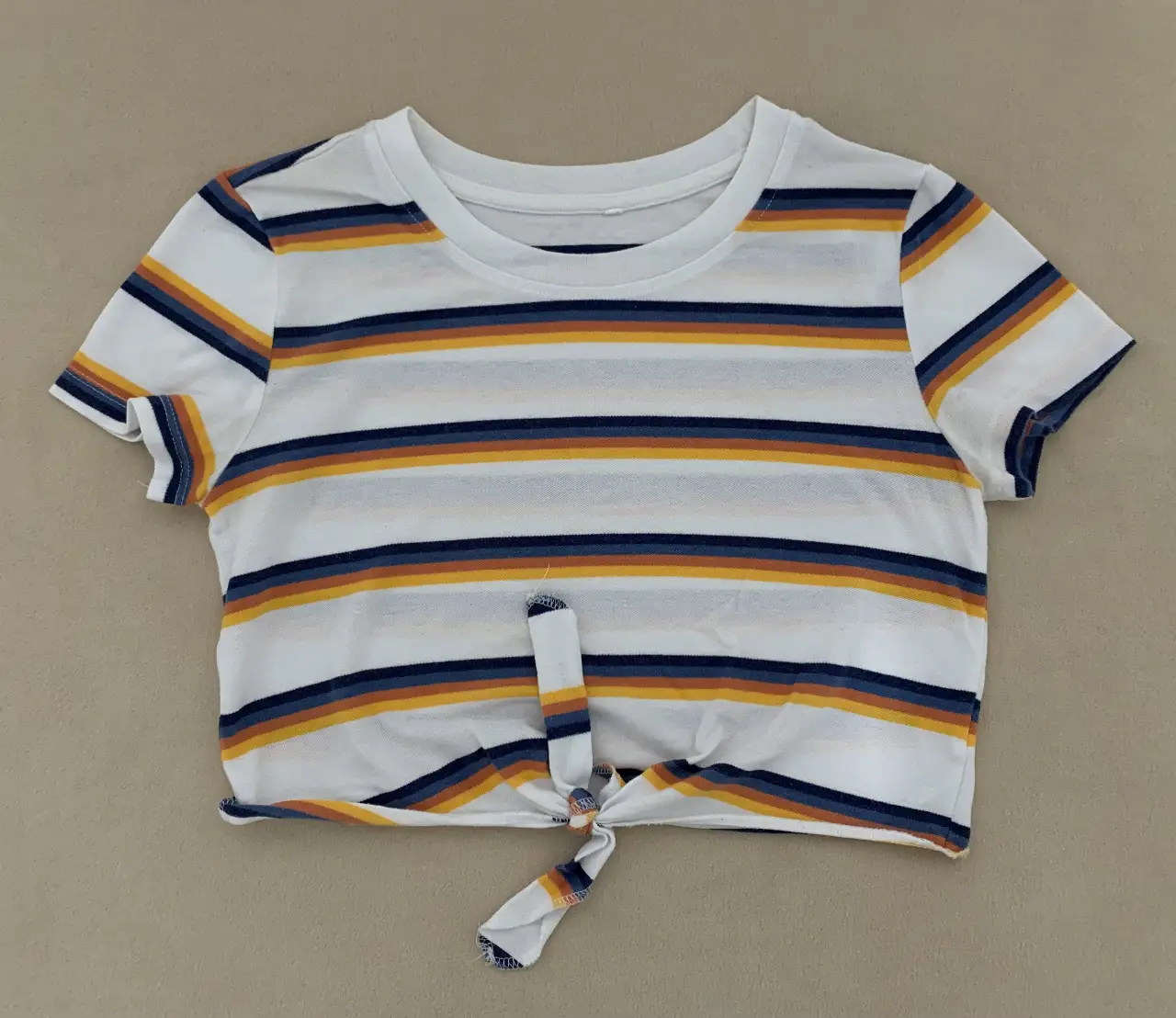 Remera crop con diseño a rayas horizontales en blanco, azul, amarillo y naranja. Ideal para un look casual y moderno.