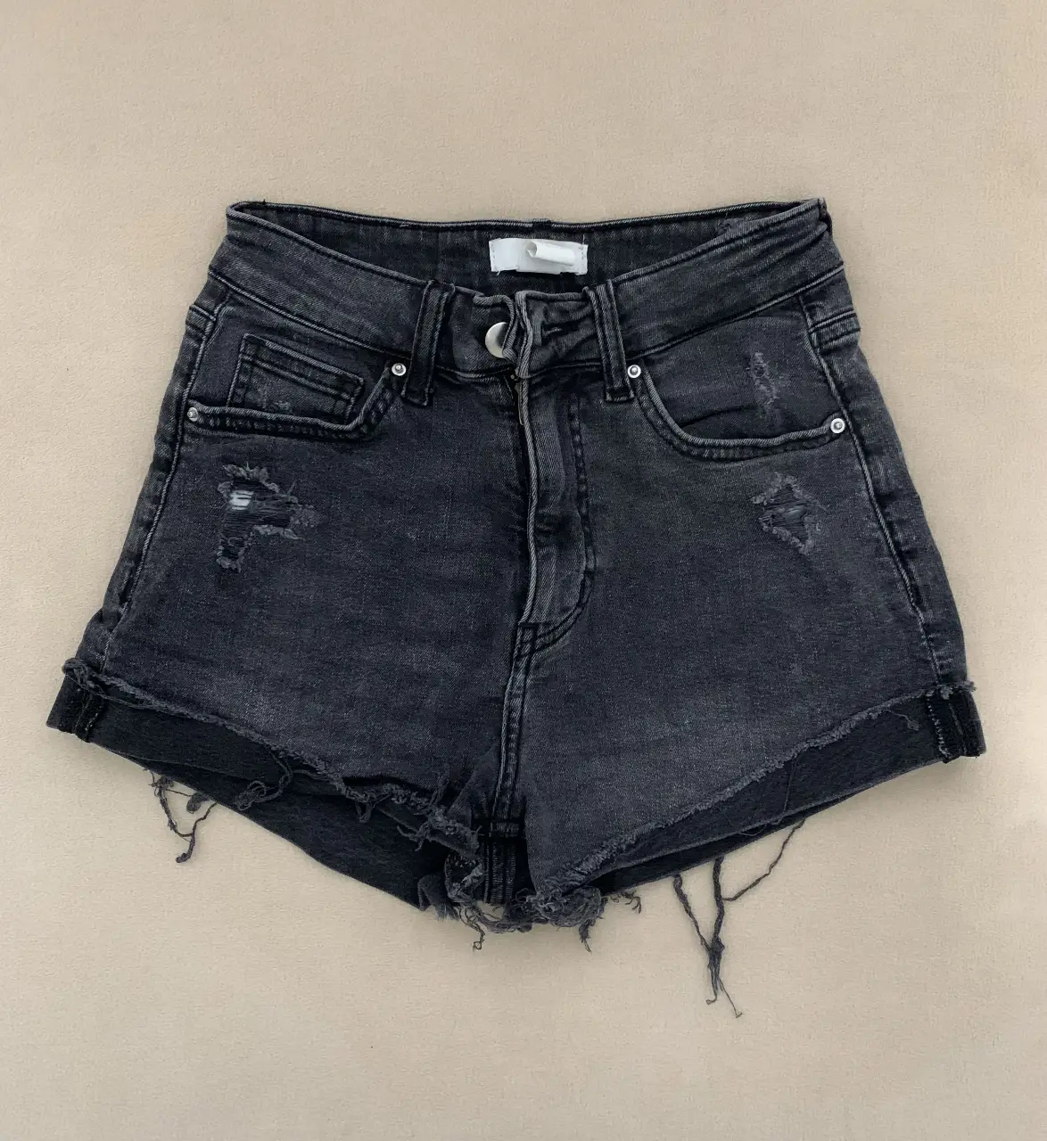 Short de jean negro con detalles rotos y desflecado. Tiro medio, ideal para un look casual y moderno. Marca H&M.