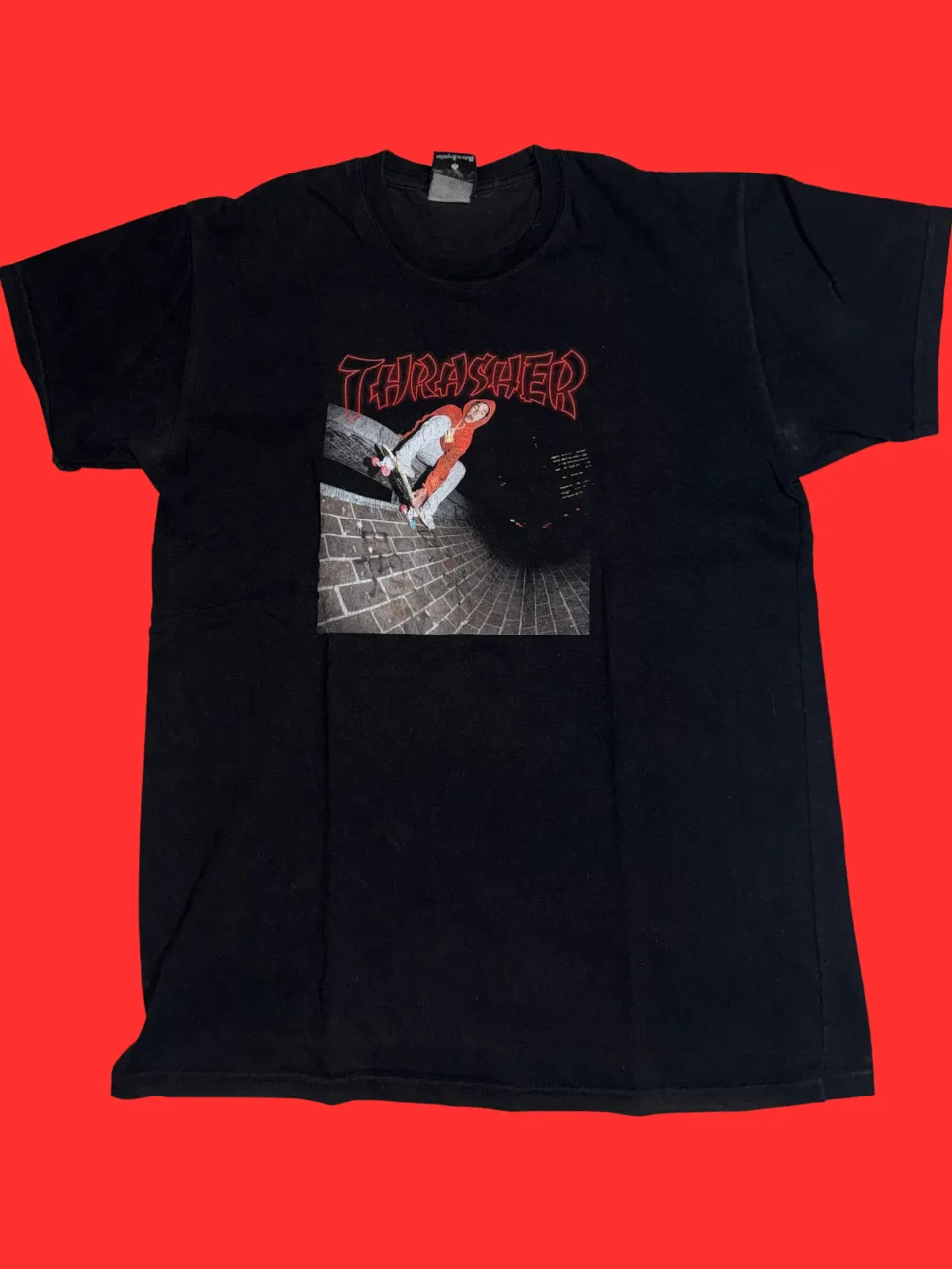 Remera negra de manga corta con estampa de "Thrasher" y un skater en acción.
