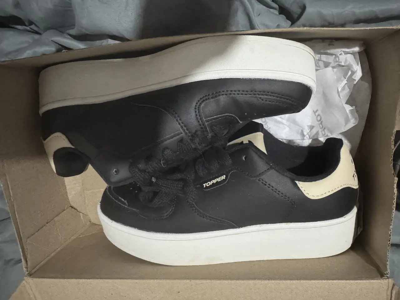 Zapatillas Topper negras con suela blanca, ideales para un look casual y urbano. Diseño moderno y cómodo, perfectas para el día a día.