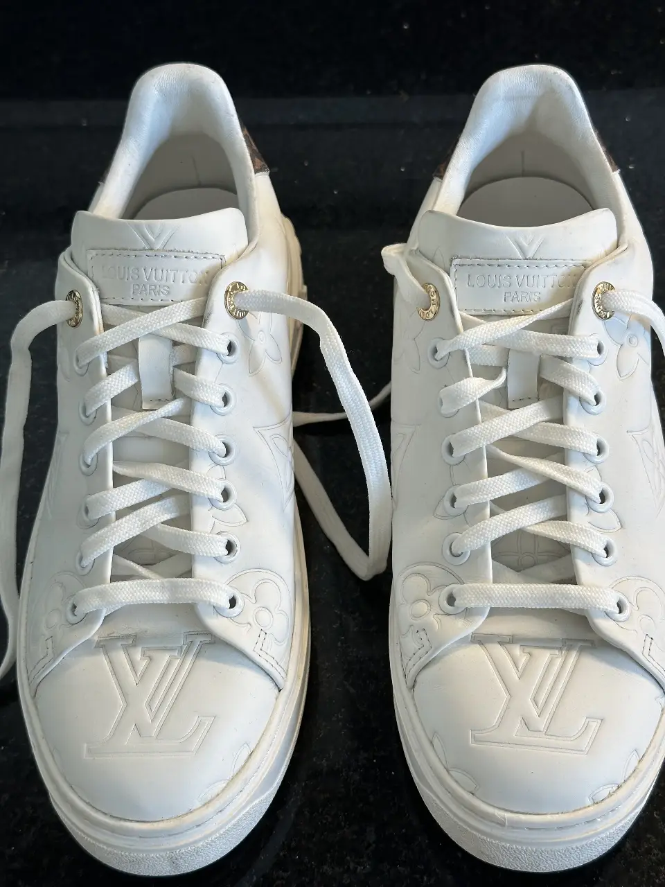 Zapatillas Louis Vuitton blancas en cueto con detalles en marrón . Diseño con el logo LV en relieve y detalles florales. Talle 40.